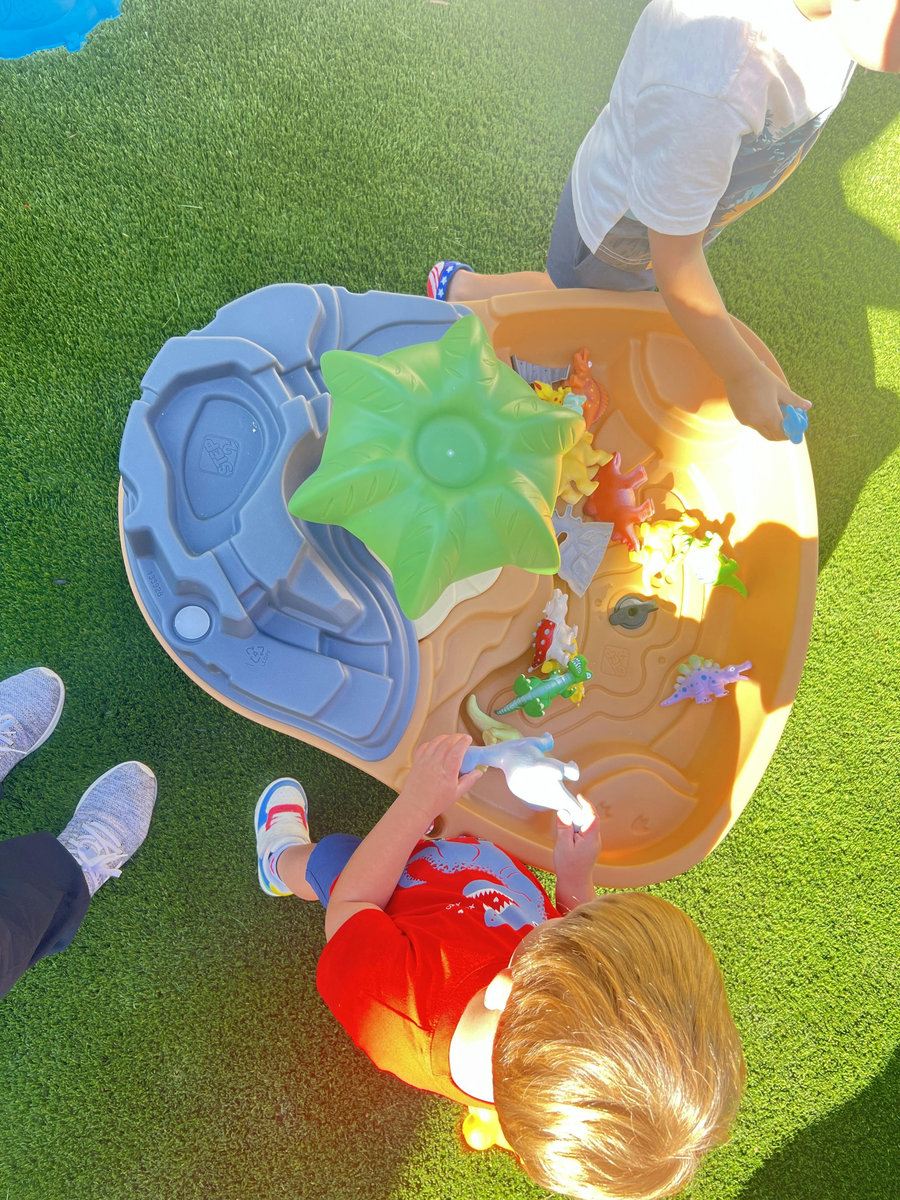 Child playing with a water table, another person standing nearby