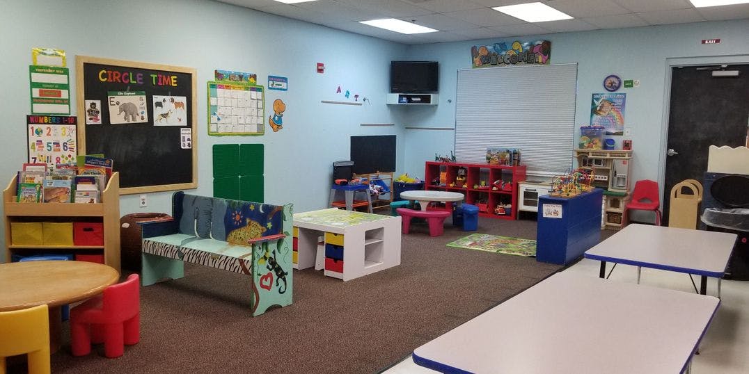 Classroom with small tables, chairs, and a chalkboard with "CIRCLE TIME"