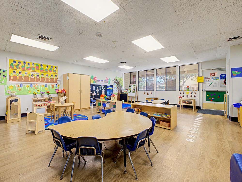 Empty preschool classroom with small tables and chairs