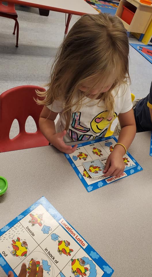Child playing a board game called "Location Lotto"