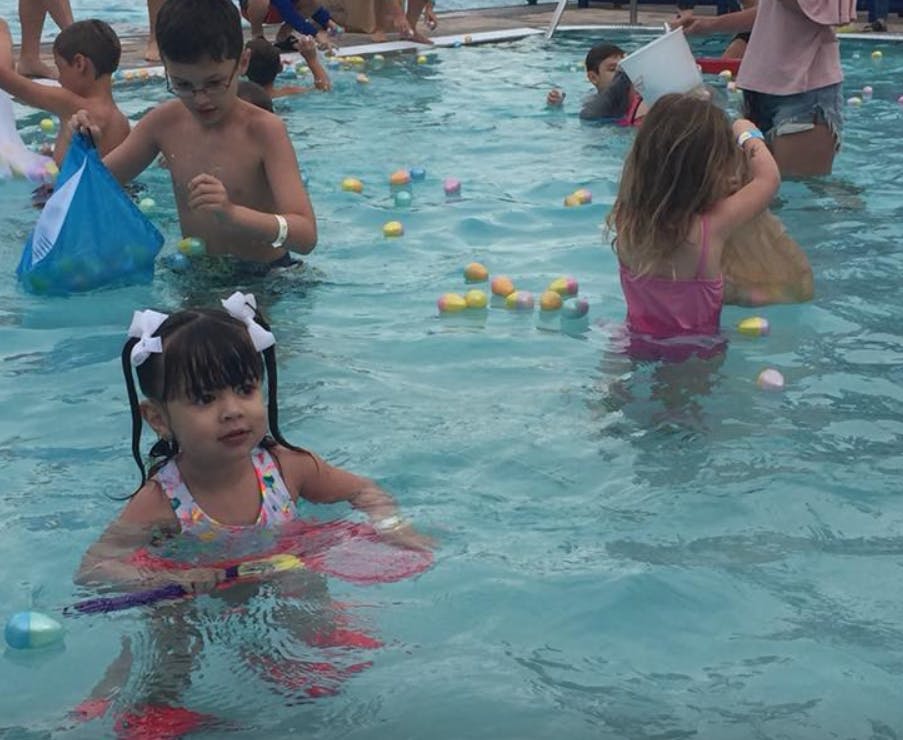 Children in a pool with floating plastic eggs