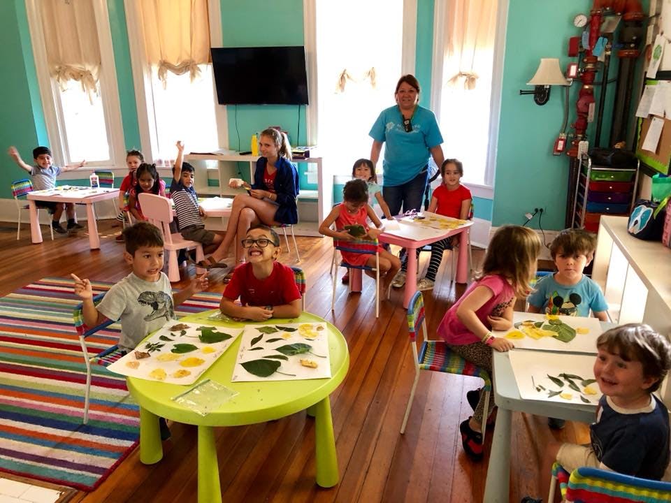 Adults and children in a classroom with children seated at tables