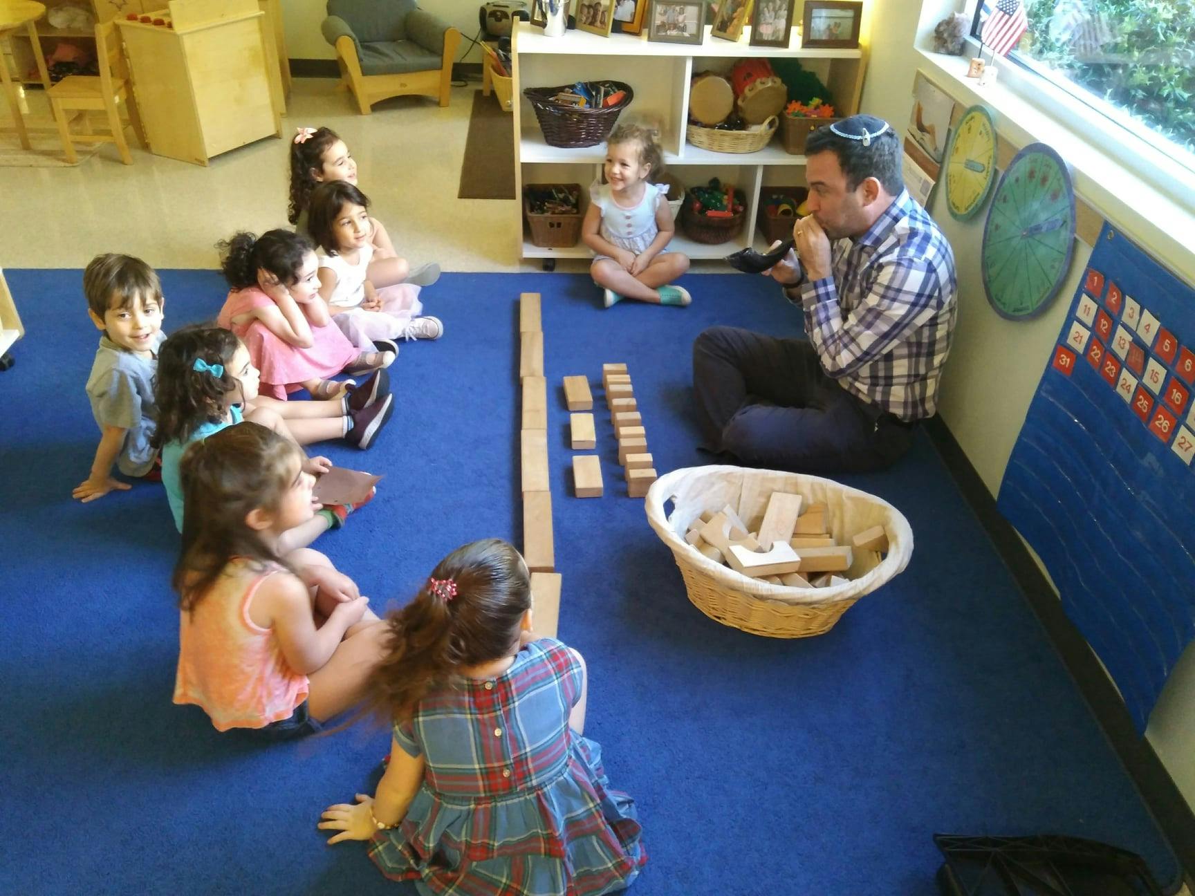 Adult and children sitting on floor with wooden blocks
