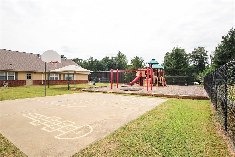 Outdoor playground with swings, slide, and basketball court