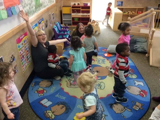Adult and children gathered on a rug in a classroom