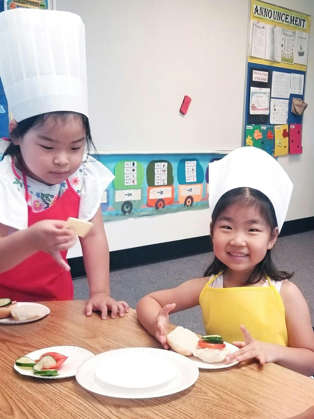 Two children in chef hats making food at a table