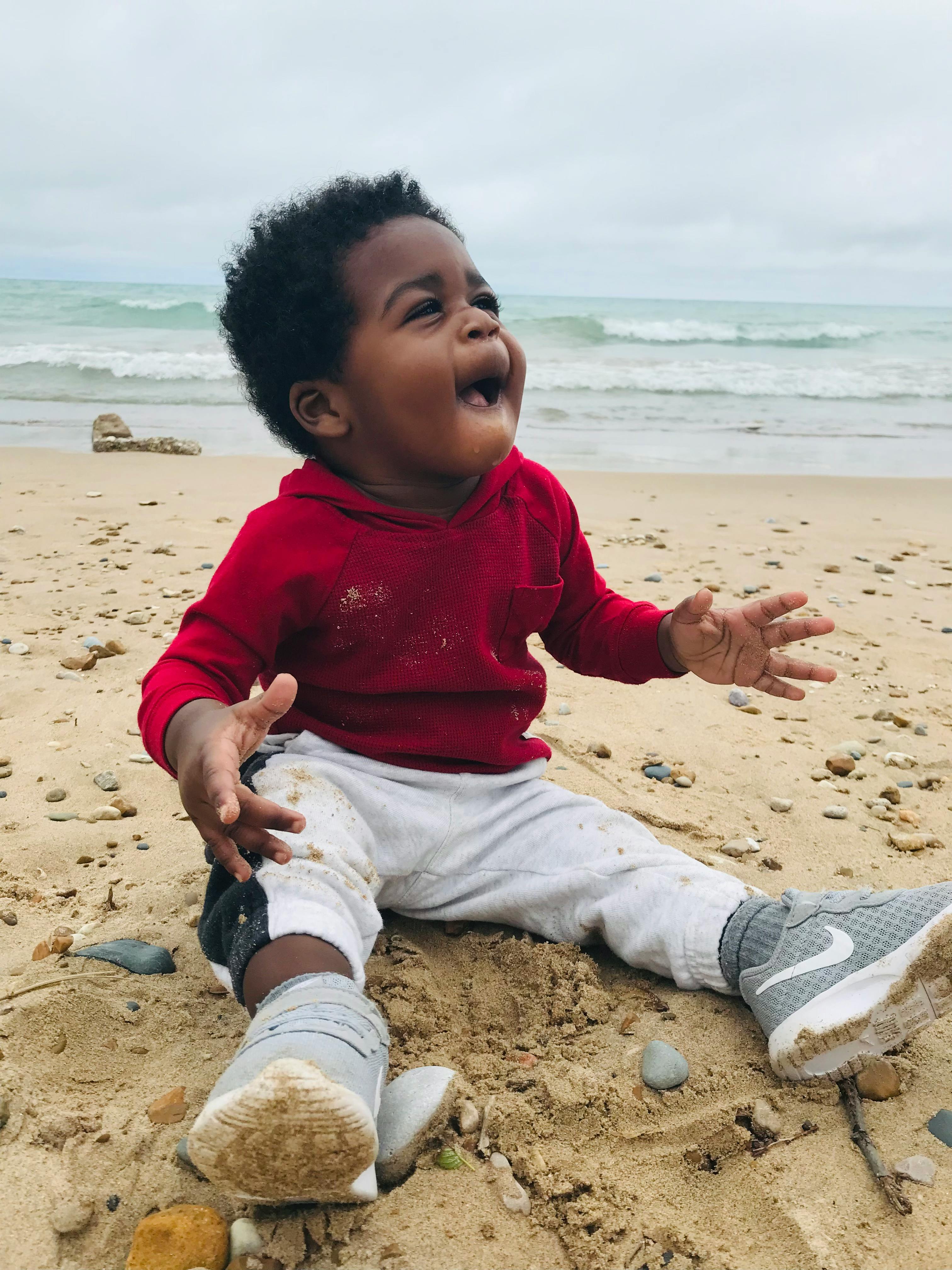 Child sitting on a sandy beach near the water