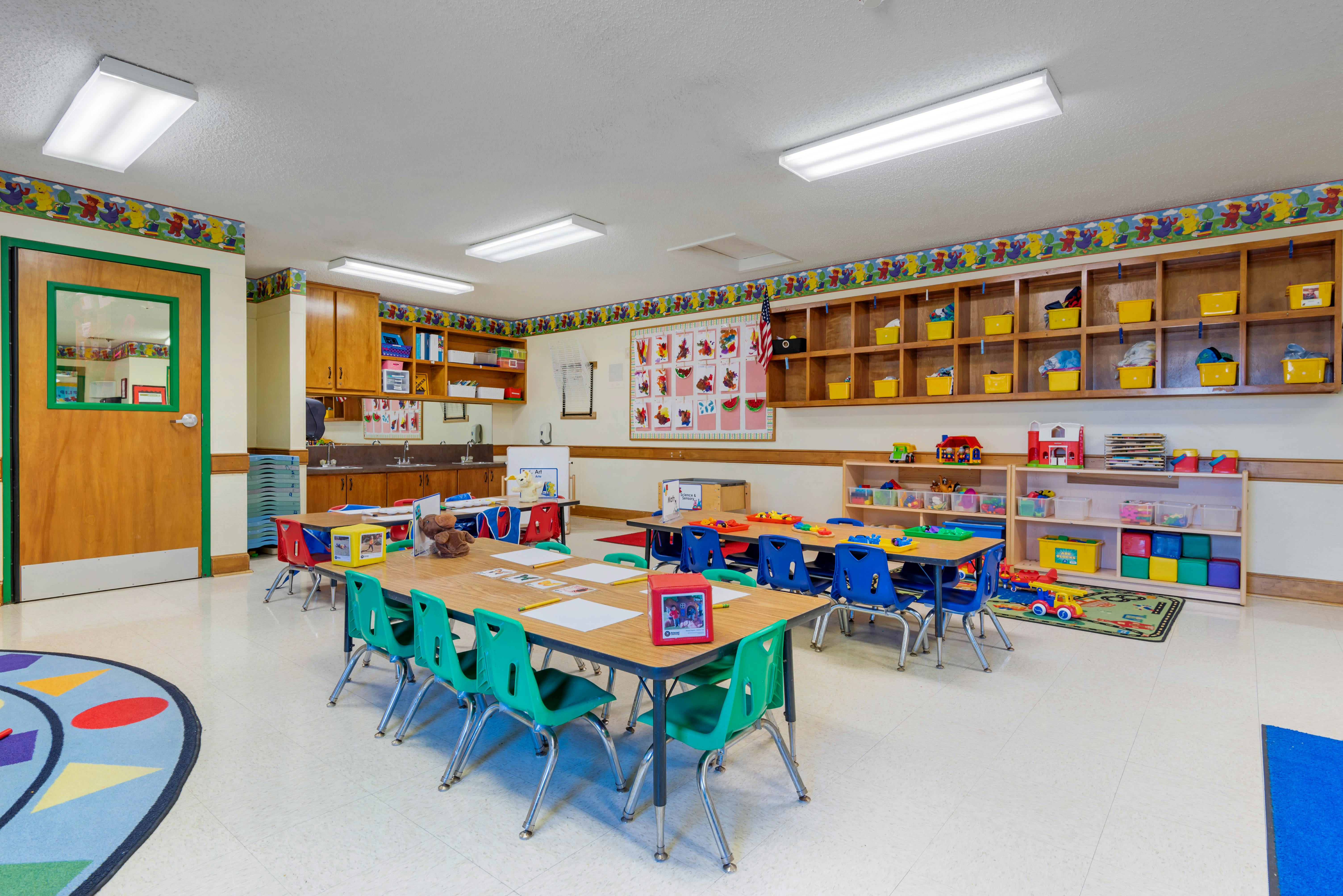 An empty colorful children's classroom with tables and chairs