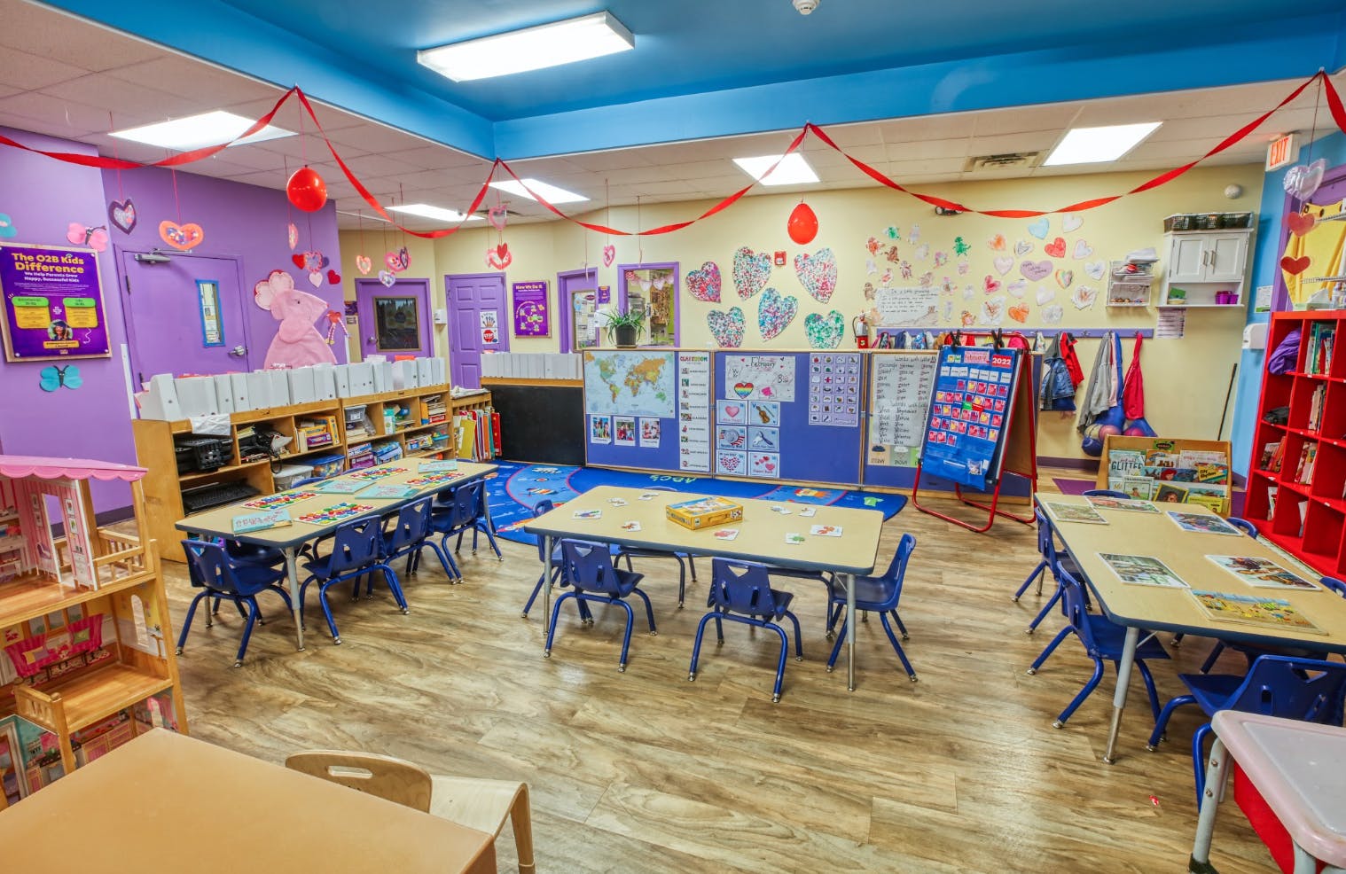 An empty colorful classroom with small tables and chairs, decorated with hearts