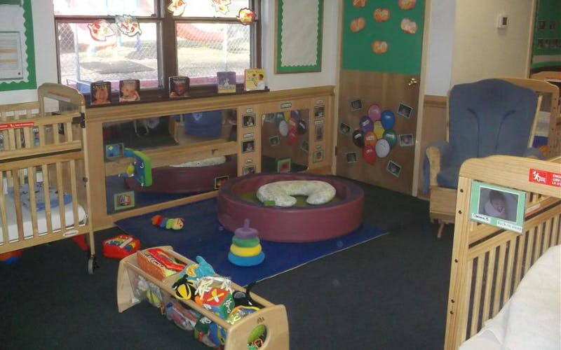 A childcare classroom with cribs, play mats, and toys