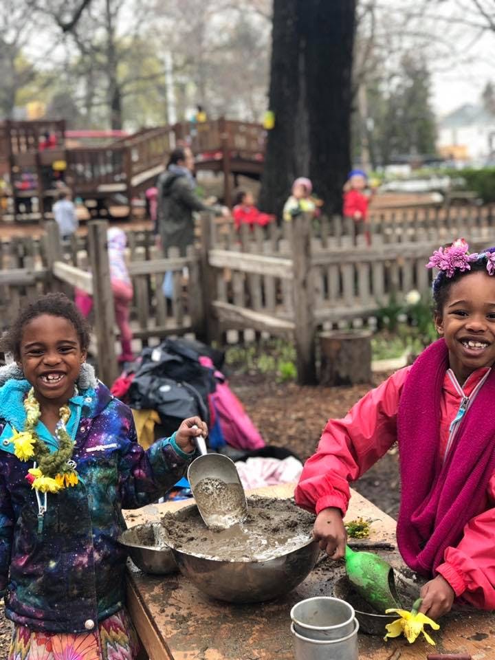 Two children playing with mud and water in bowls outdoors