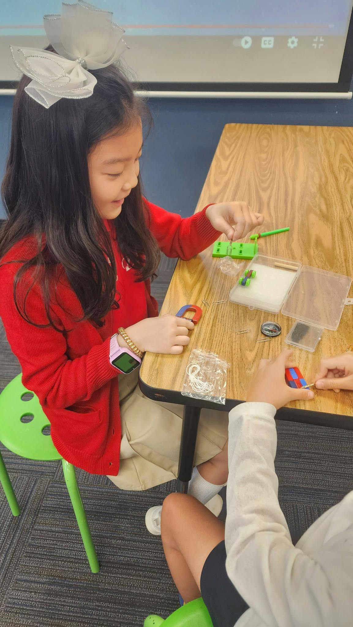Child in red shirt playing with magnets at a table