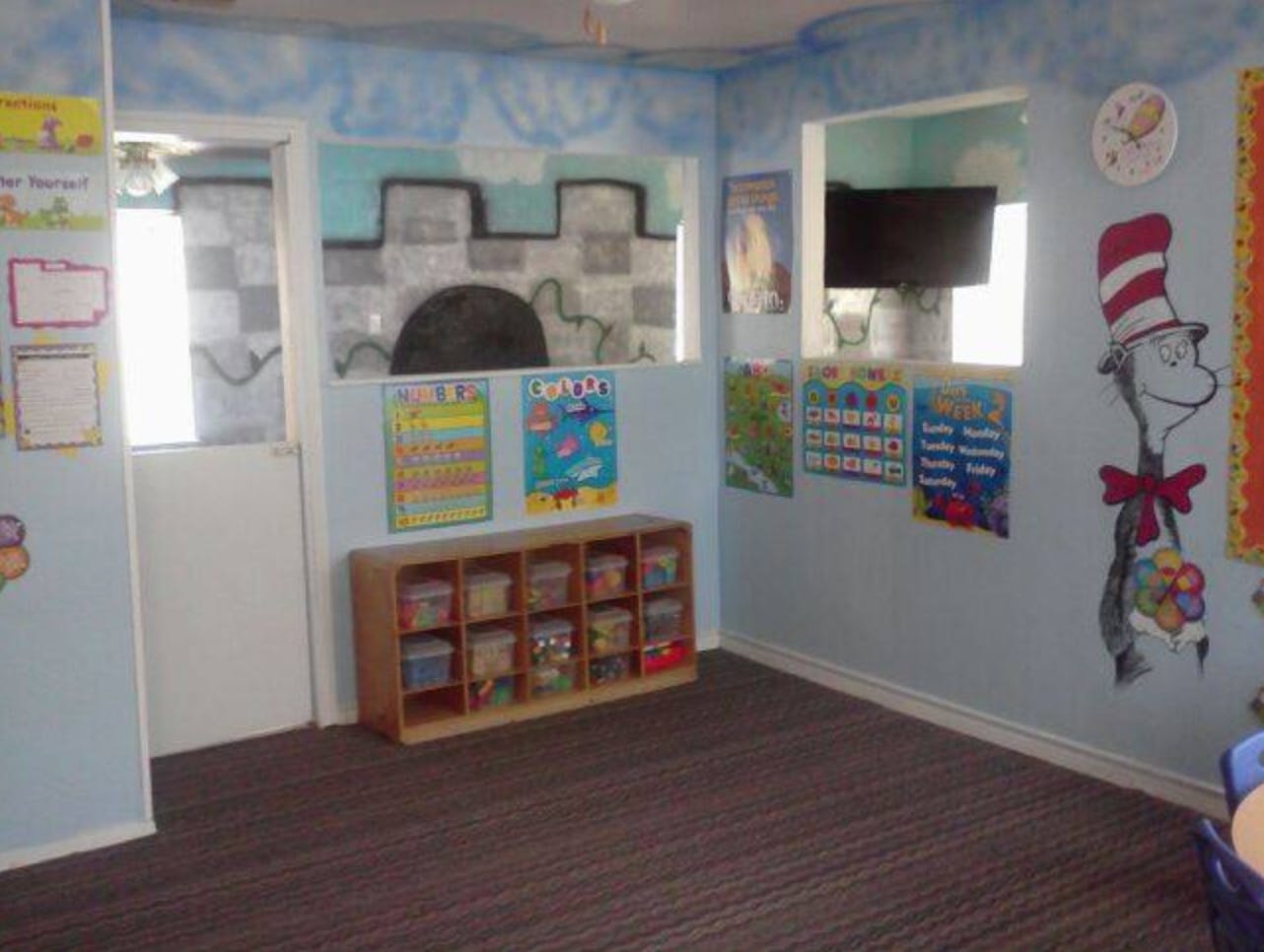 Classroom with light blue walls, windows, and a wooden storage unit