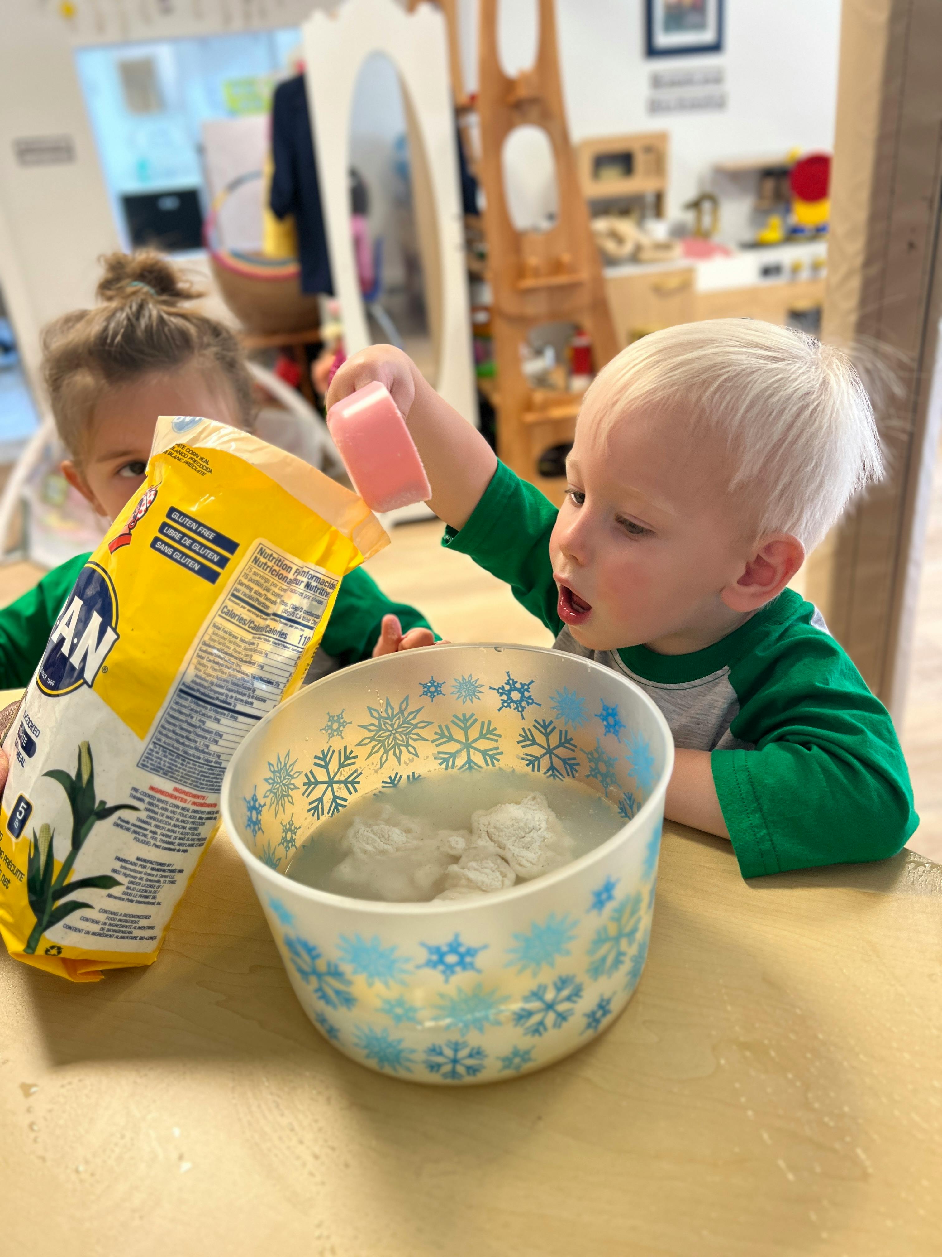 Child playing with a yellow bag and a bowl of white material
