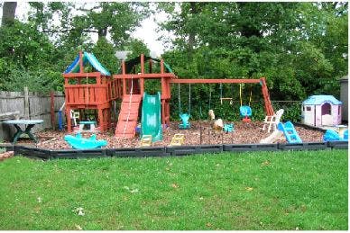 Wooden playground set with slides and swings in a grassy yard