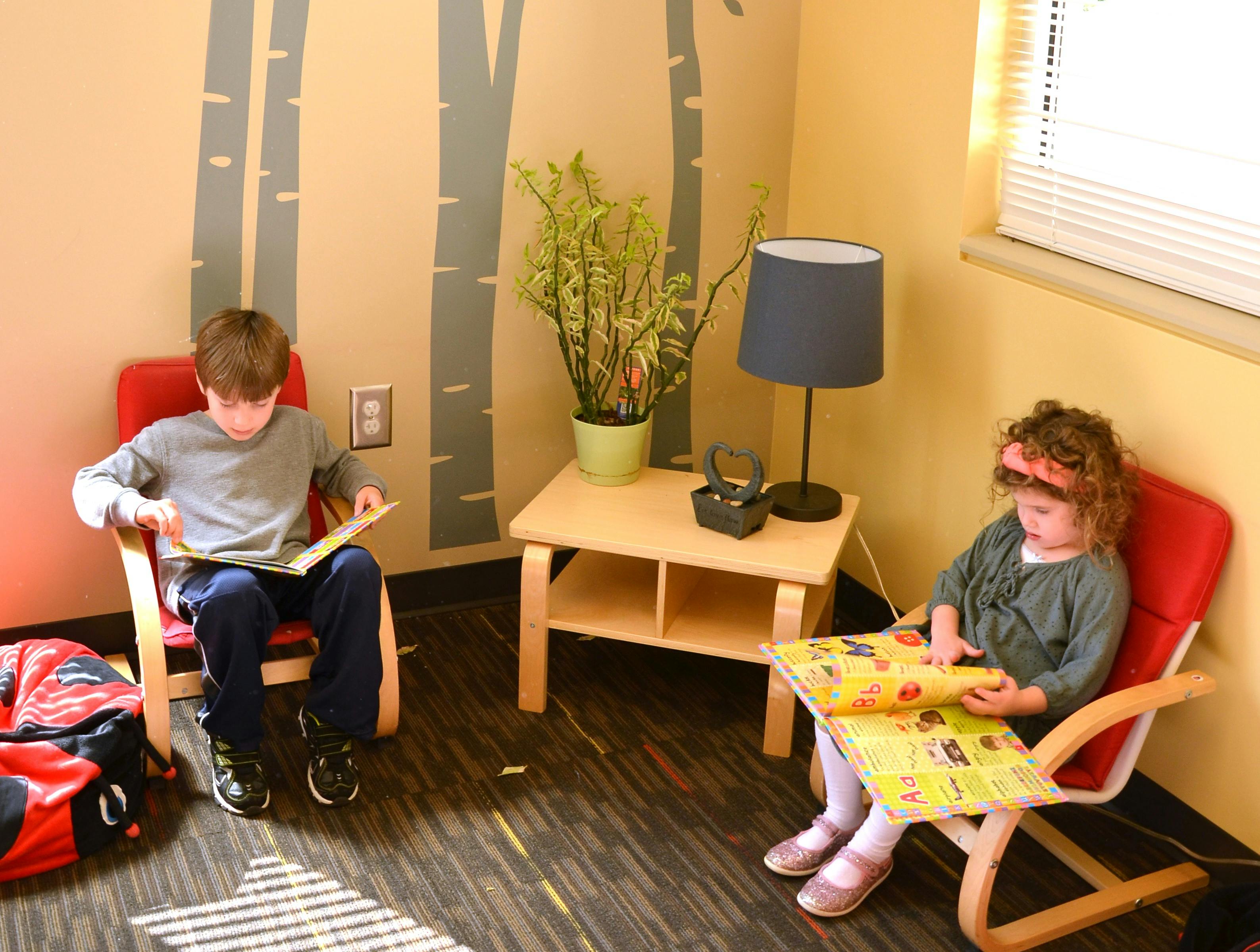 Child and teen sitting in chairs reading books