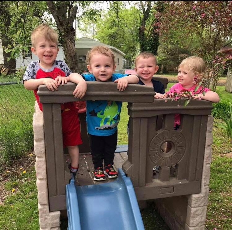 Four children on a playground structure with a slide