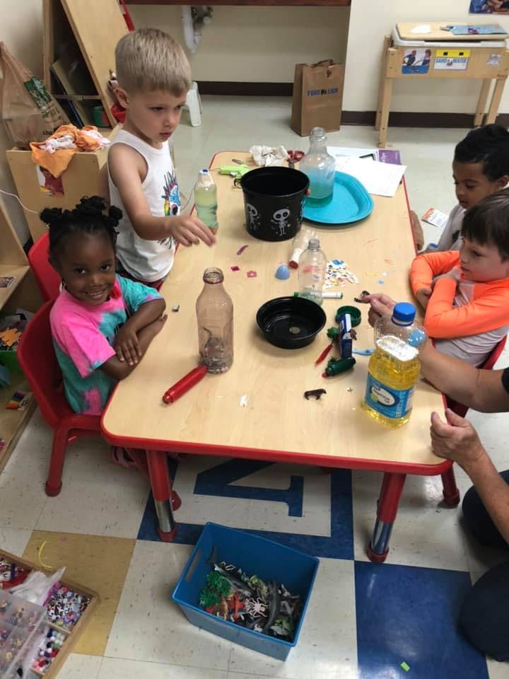 Children at a table with various items, including bottles and bowls