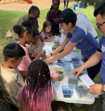People and children gathered around a table with containers