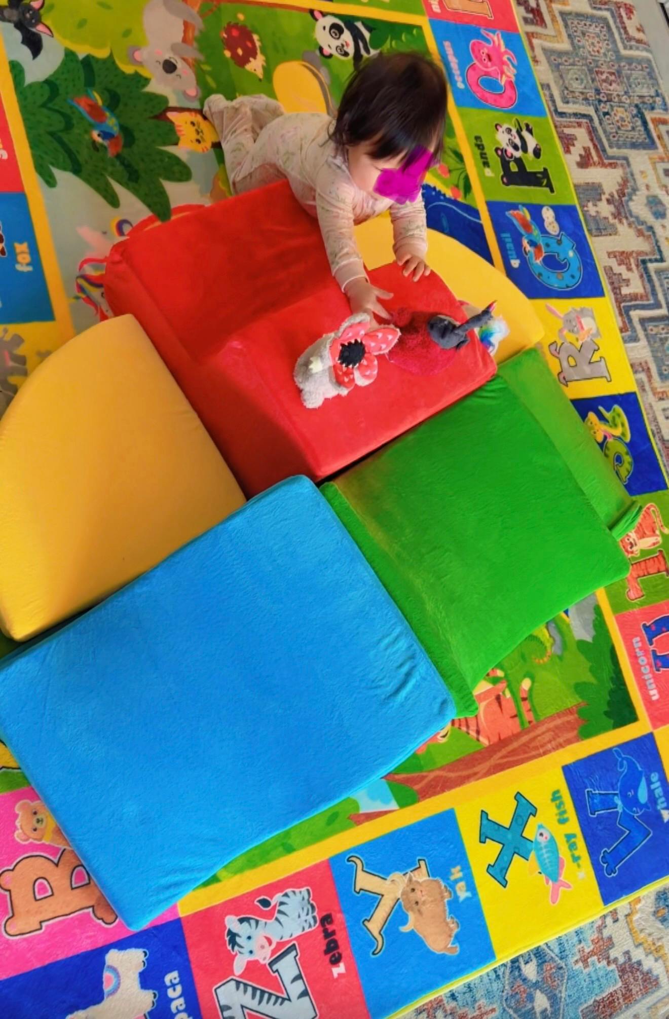 Child playing with plush toys on colorful foam mats