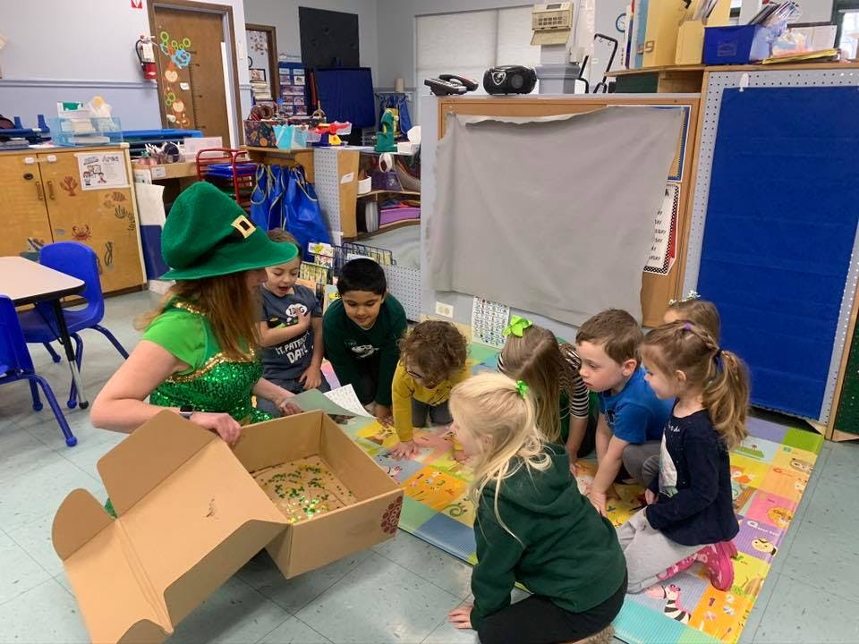 Person in green hat with children looking into a box
