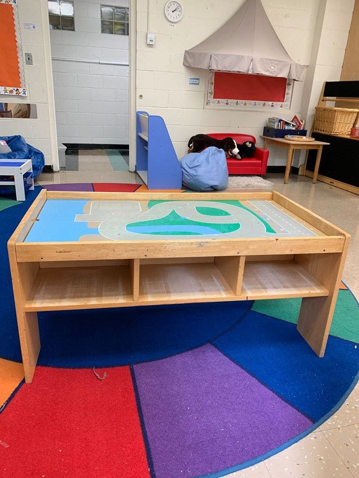 Playroom with a wooden activity table on a colorful rug