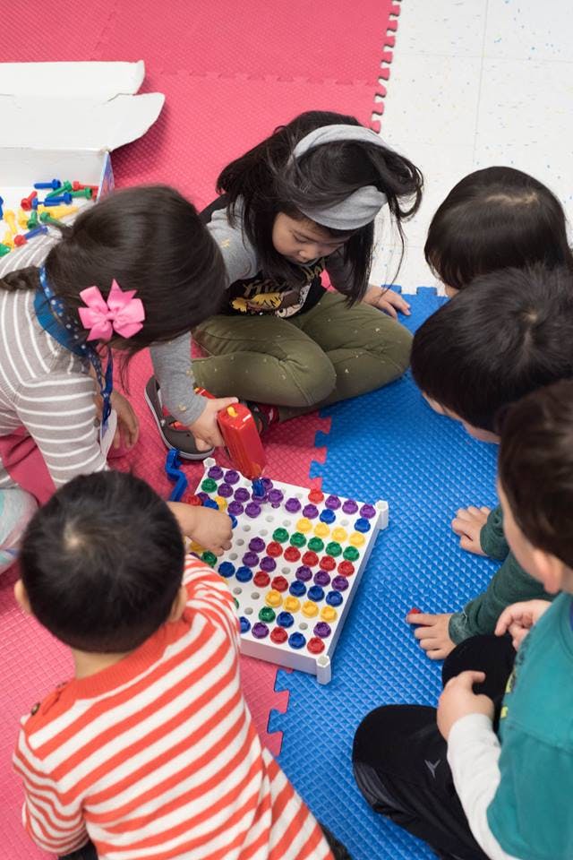 Children playing with a colorful pegboard game on a mat