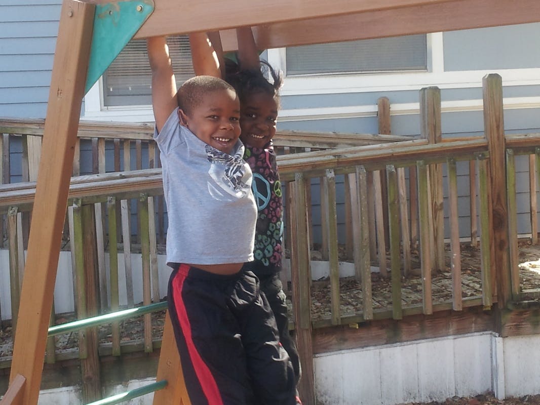 Two children hanging from monkey bars