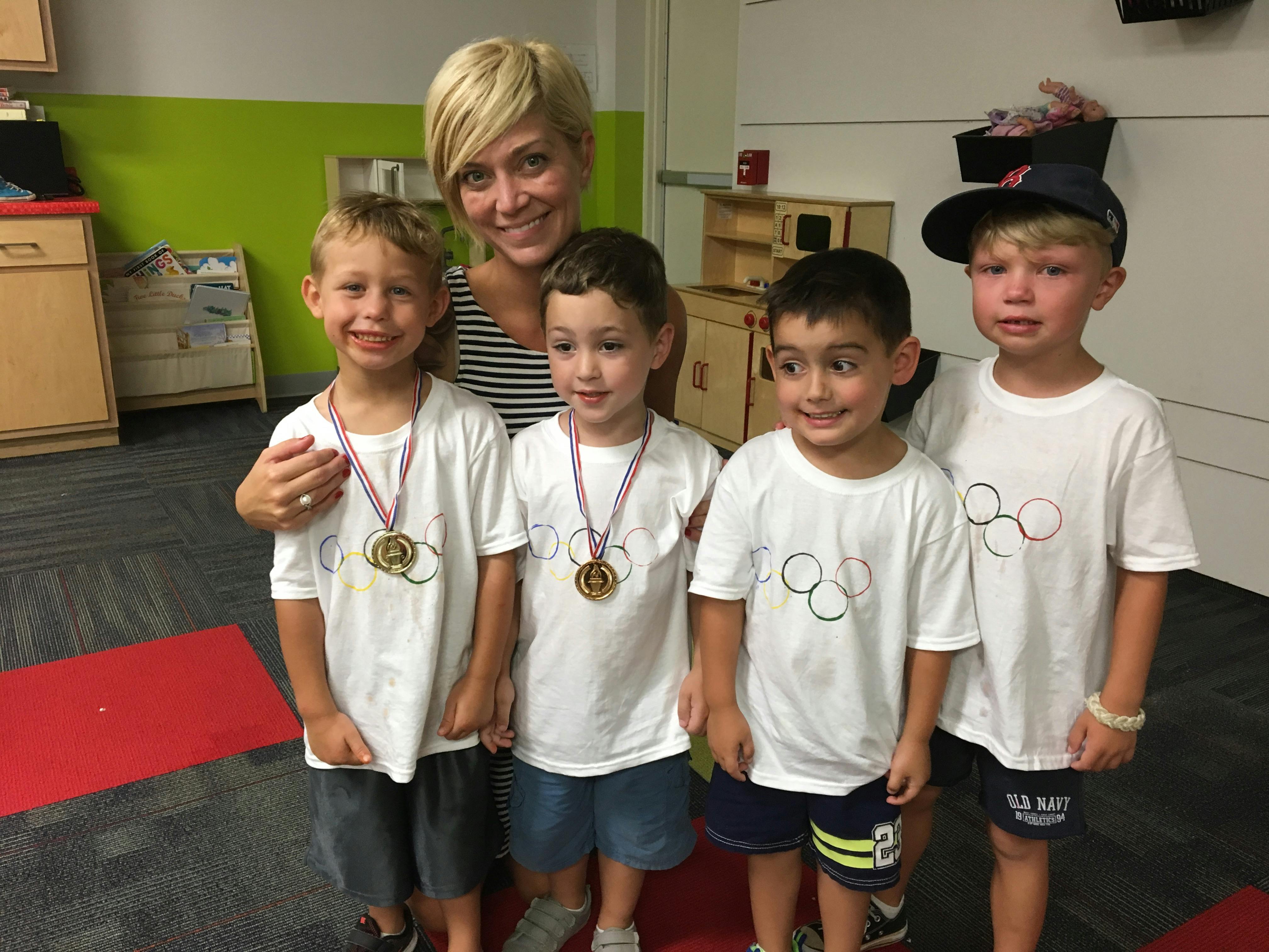 Adult person with four children wearing medals and white shirts