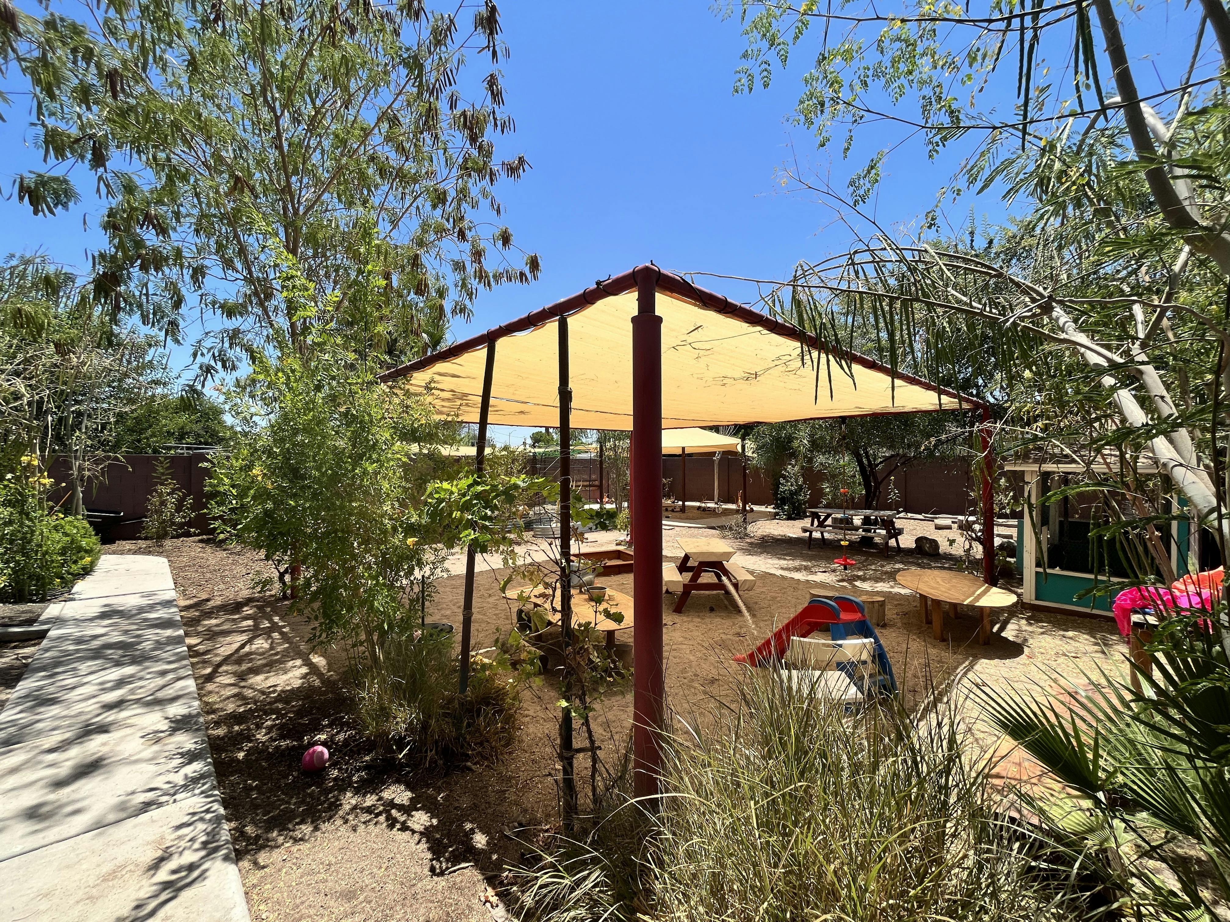 Outdoor play area with shade structures and picnic tables