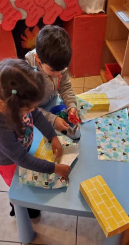 Two children wrapping gifts at a table