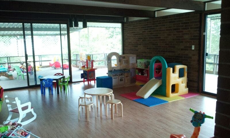 Indoor play area with small tables, chairs, and a plastic slide structure