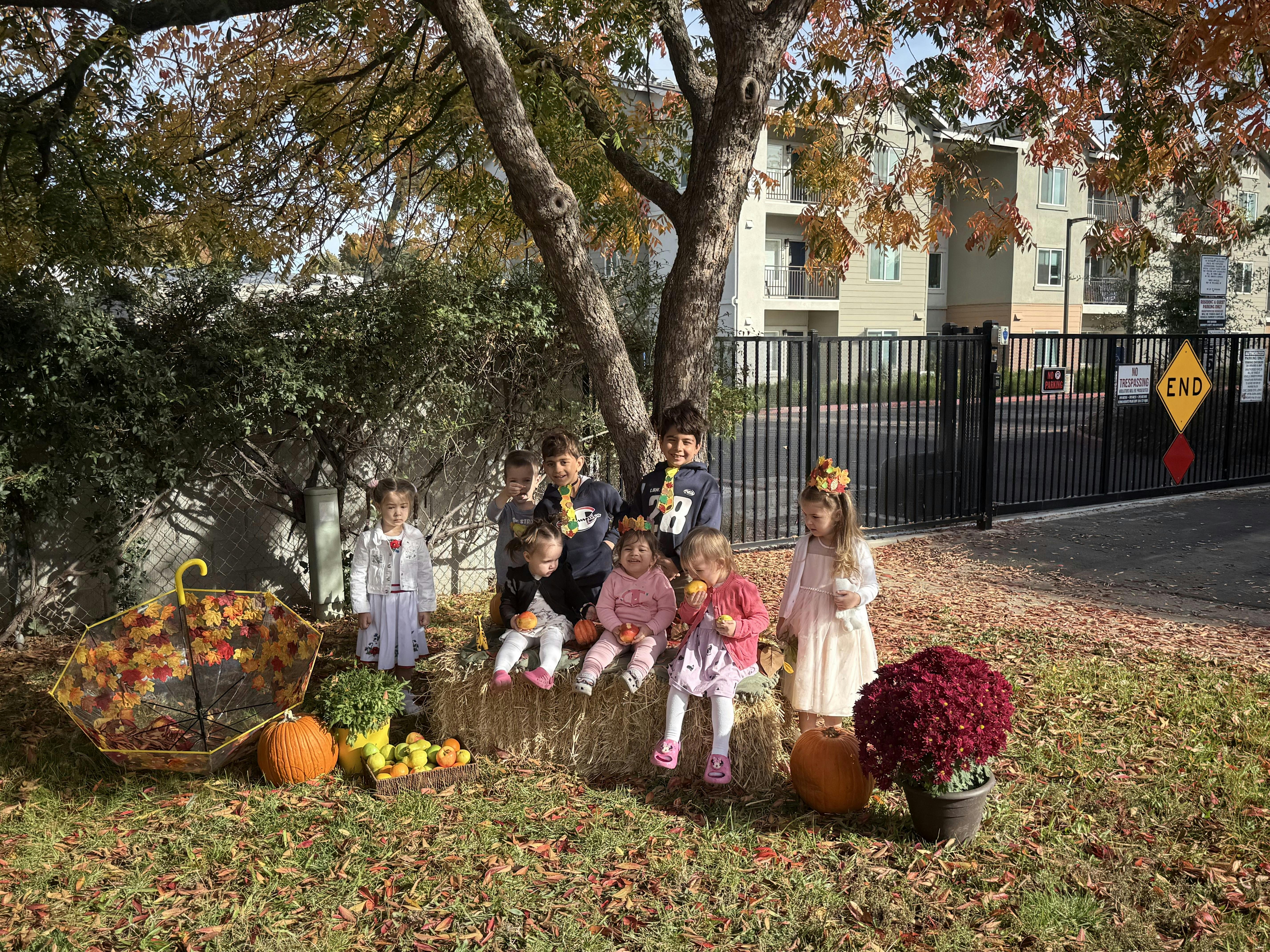Children sitting on hay bales with fall decorations