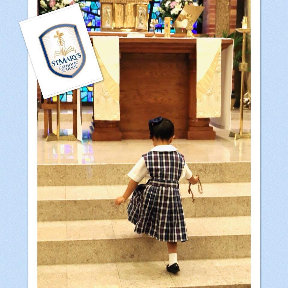Child in plaid uniform walking up steps in a church