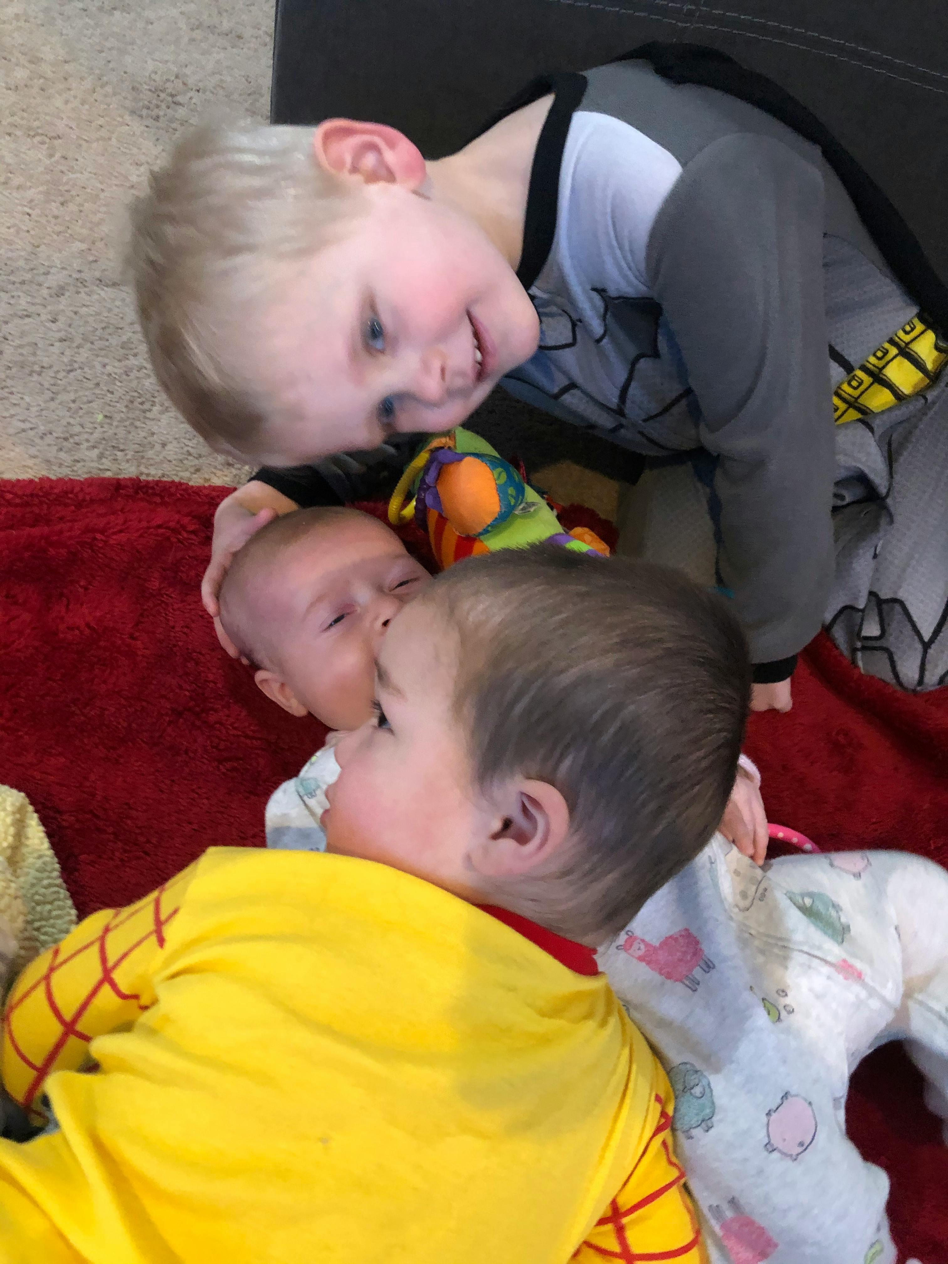 Three children on a red blanket, one child looking at two infants