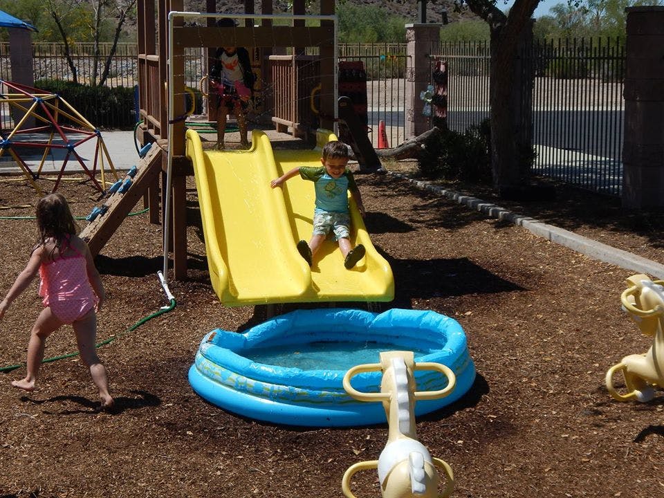 Child sliding down a yellow slide into a small blue pool