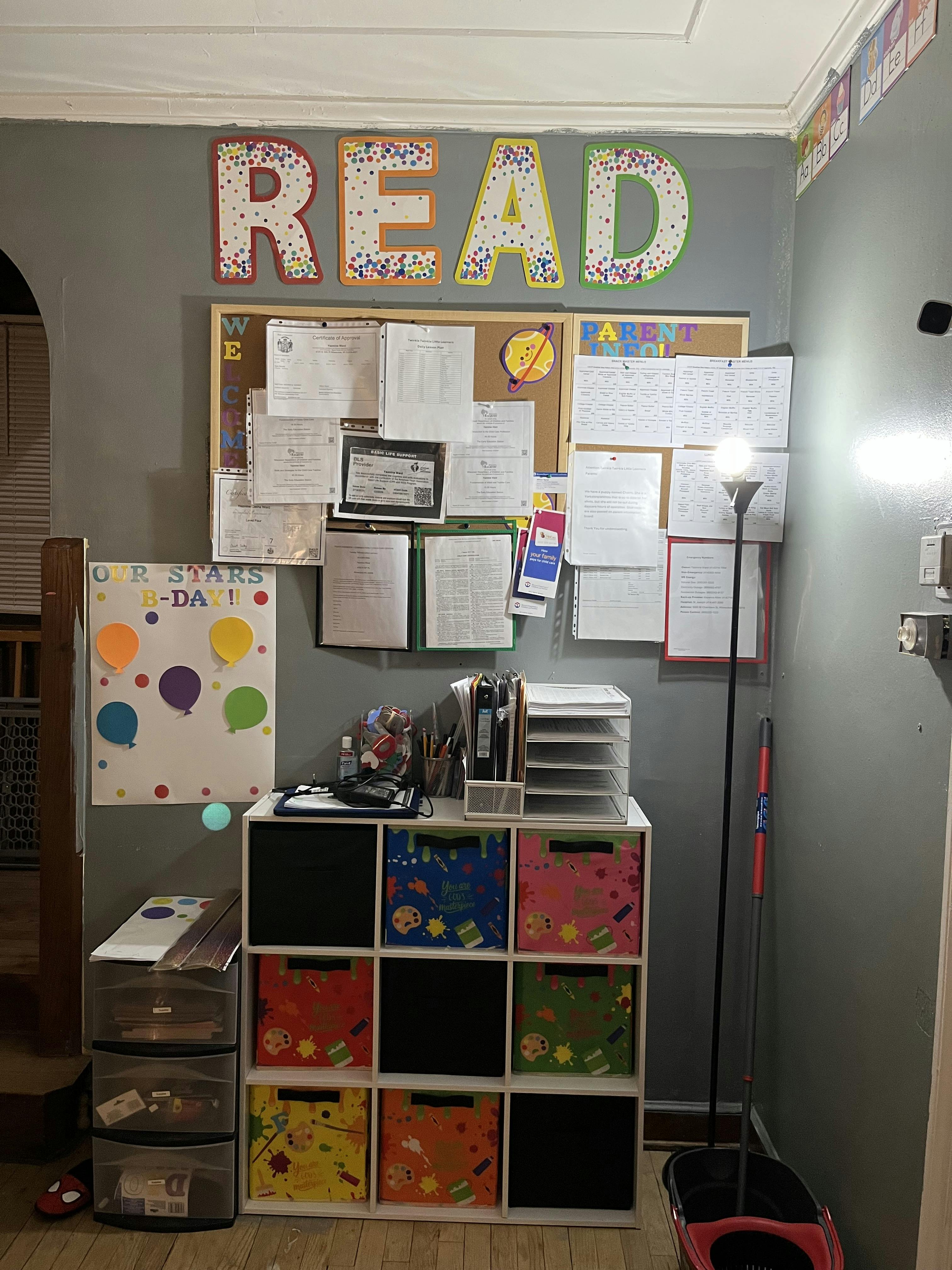 Wall with a bulletin board, storage cubbies, and a sign that says "READ"