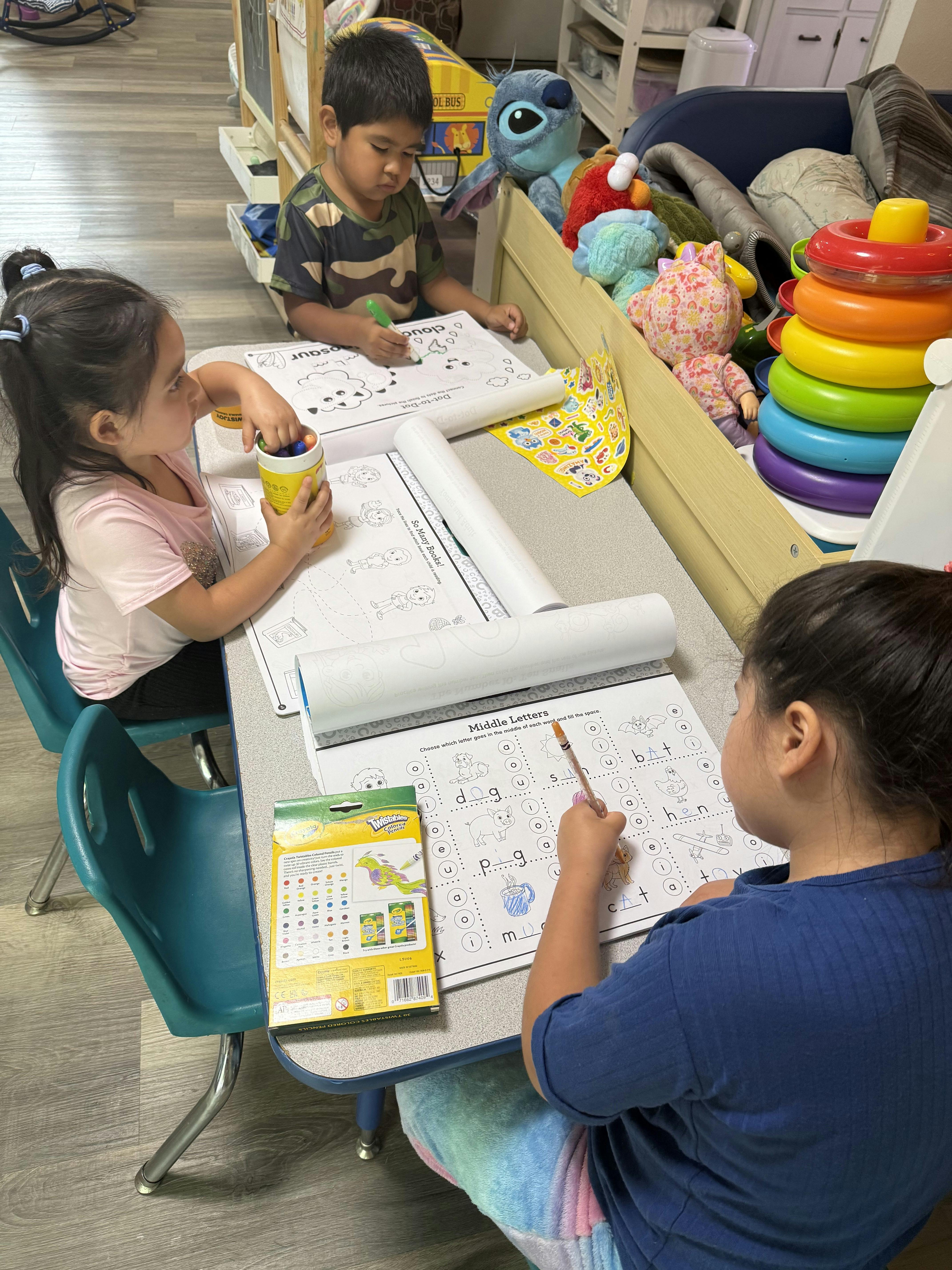 Three children working on activity worksheets at a classroom table
