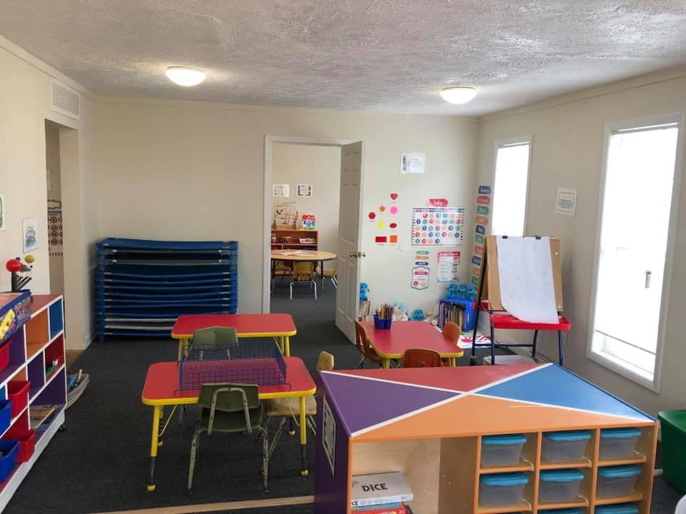 Classroom with small tables and chairs, storage units, and an easel