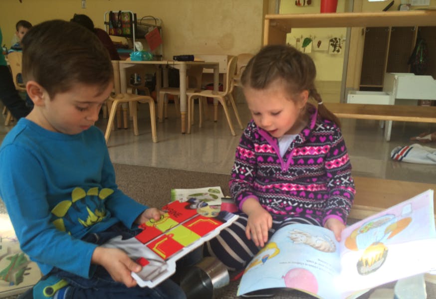 Two children sitting on the floor looking at books