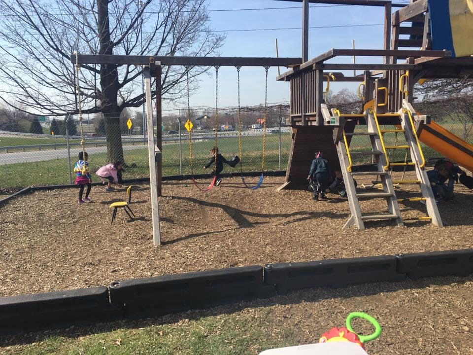 Children playing on a swing set and playground structure