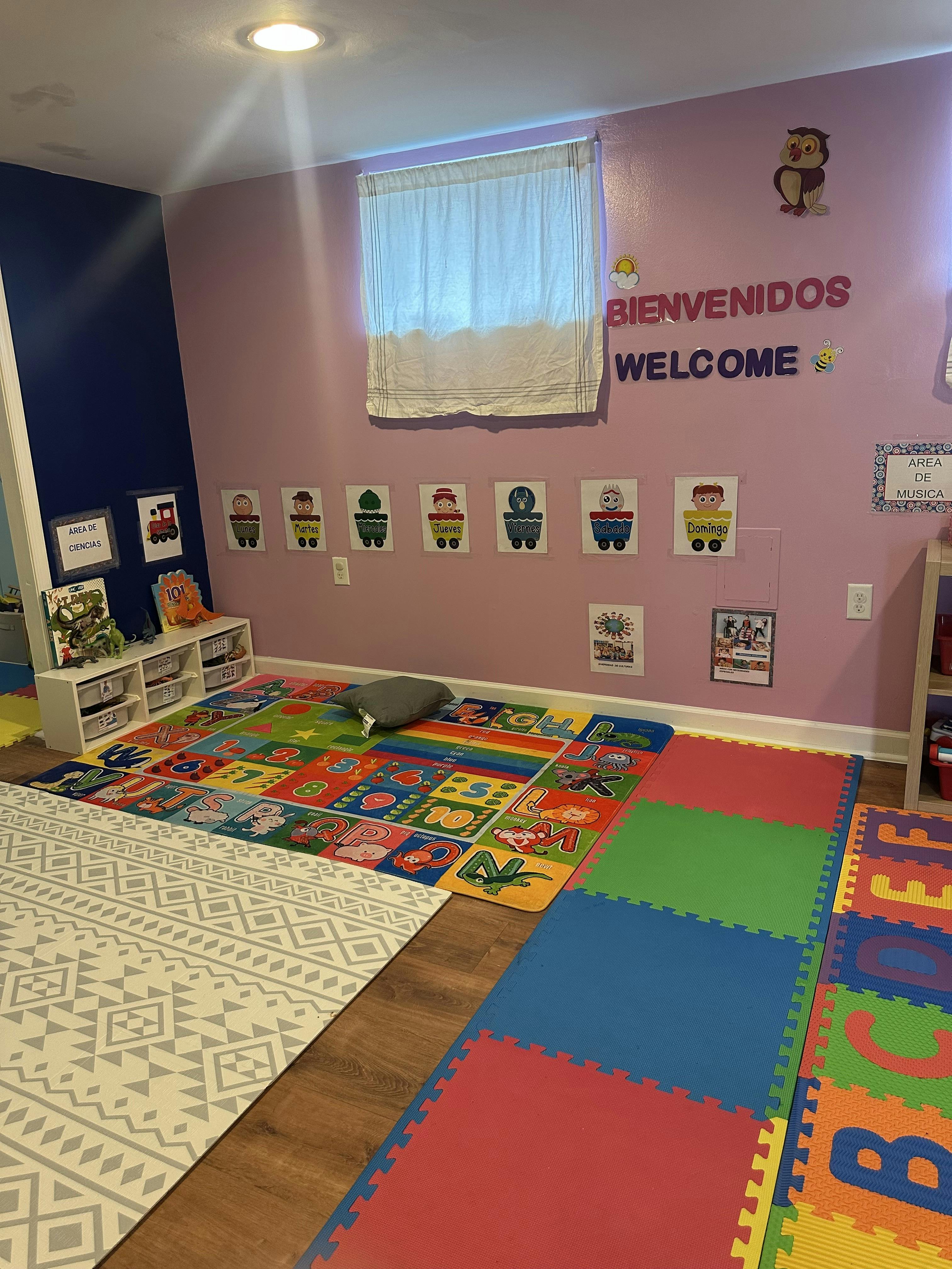 Playroom with colorful alphabet rug and foam mats, welcome sign on wall