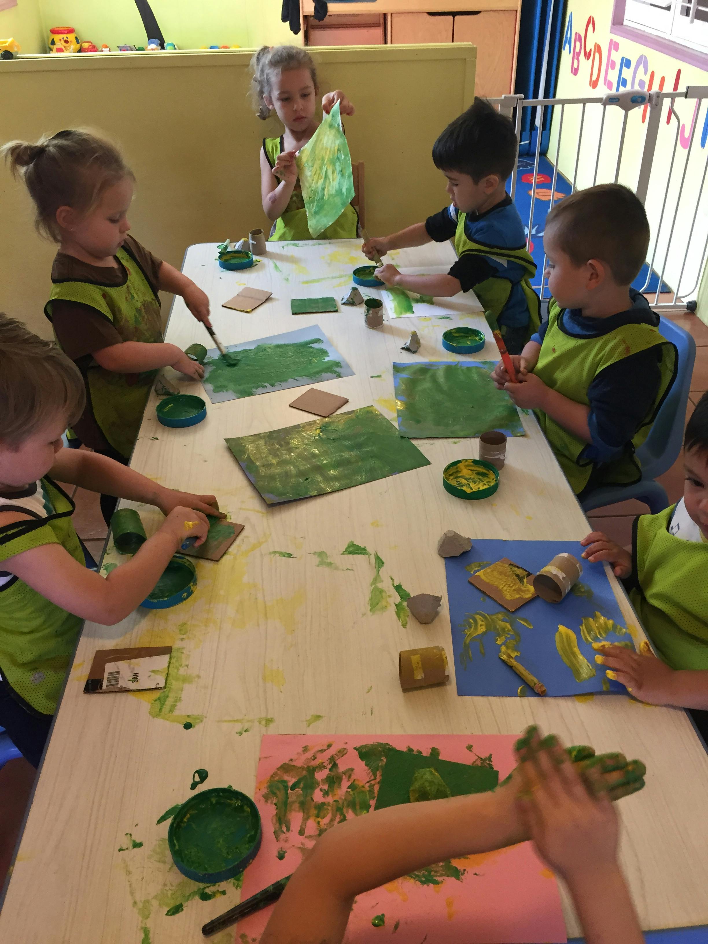 Children painting at a table in a classroom