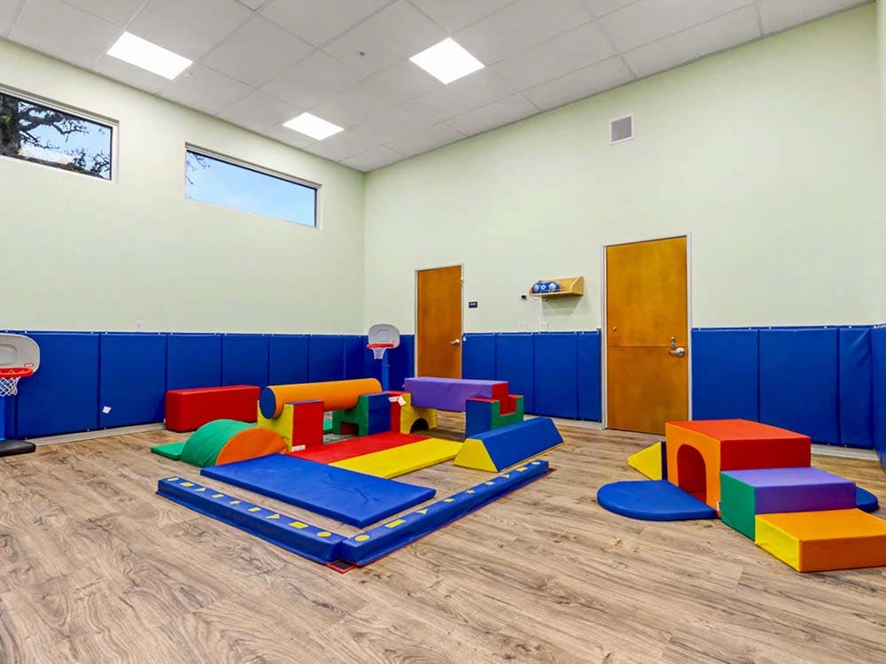 Colorful soft play equipment for children in a room with blue padded walls