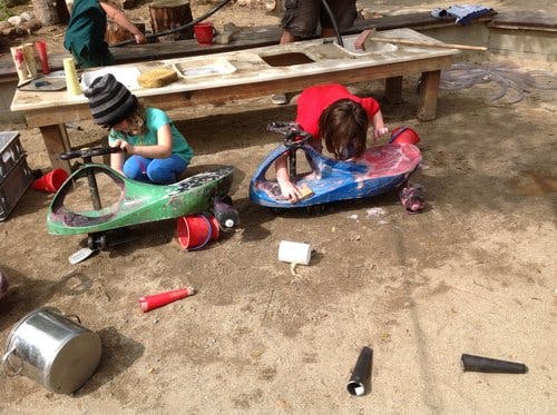 Two children playing with toy cars on the ground