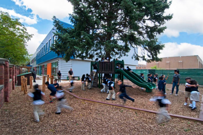 Children playing on a playground with a slide and climbing structure