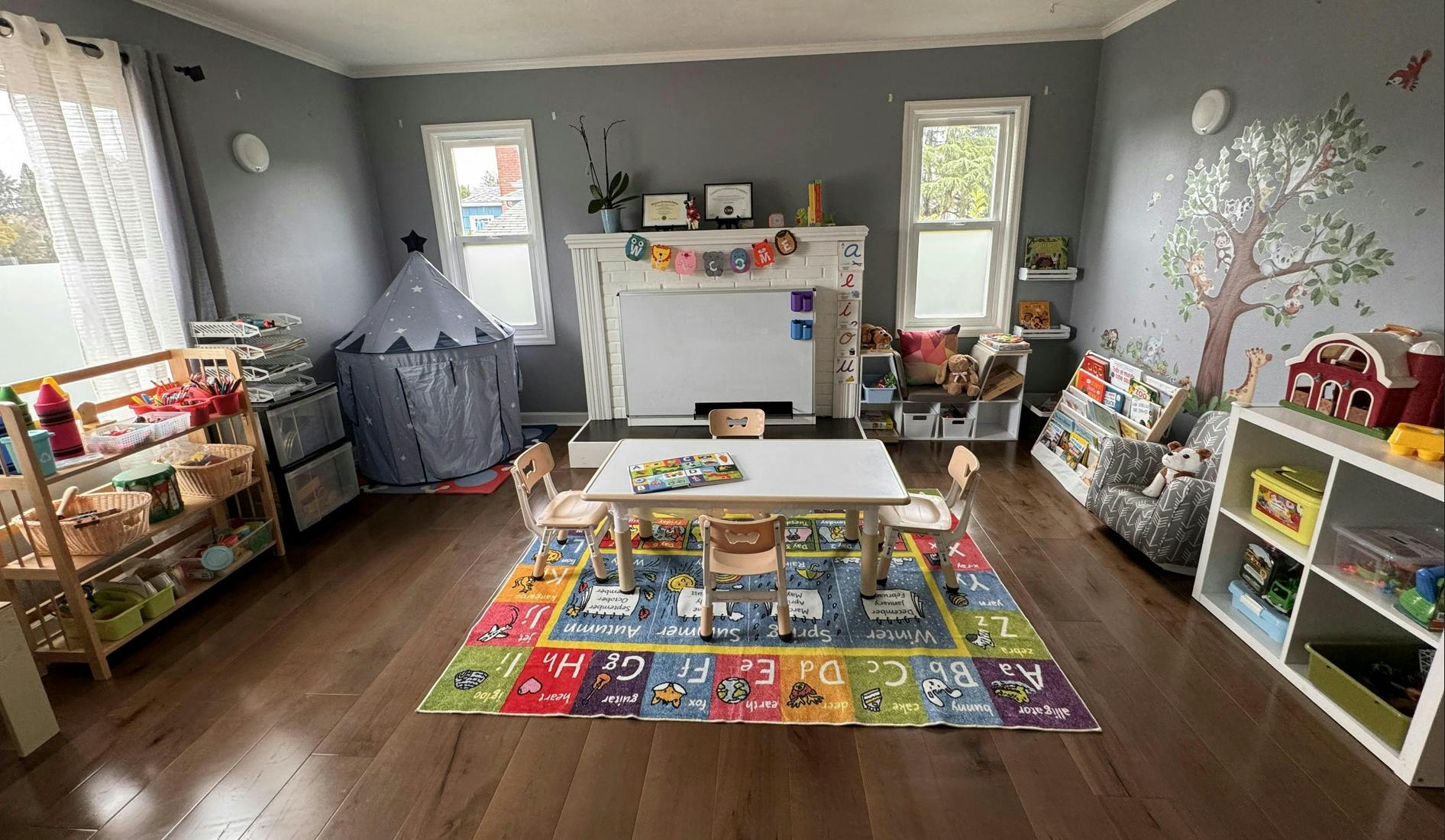 children's classroom with small table and chairs on alphabet rug, whiteboard, and toys