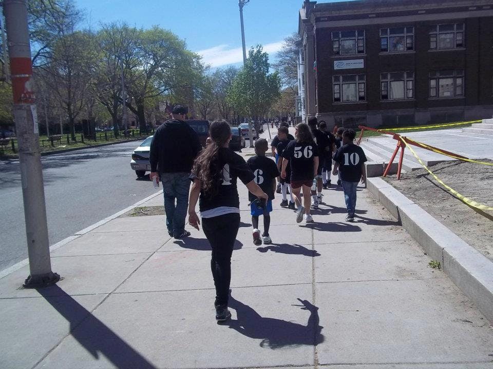 People walking on a sidewalk next to a street and building