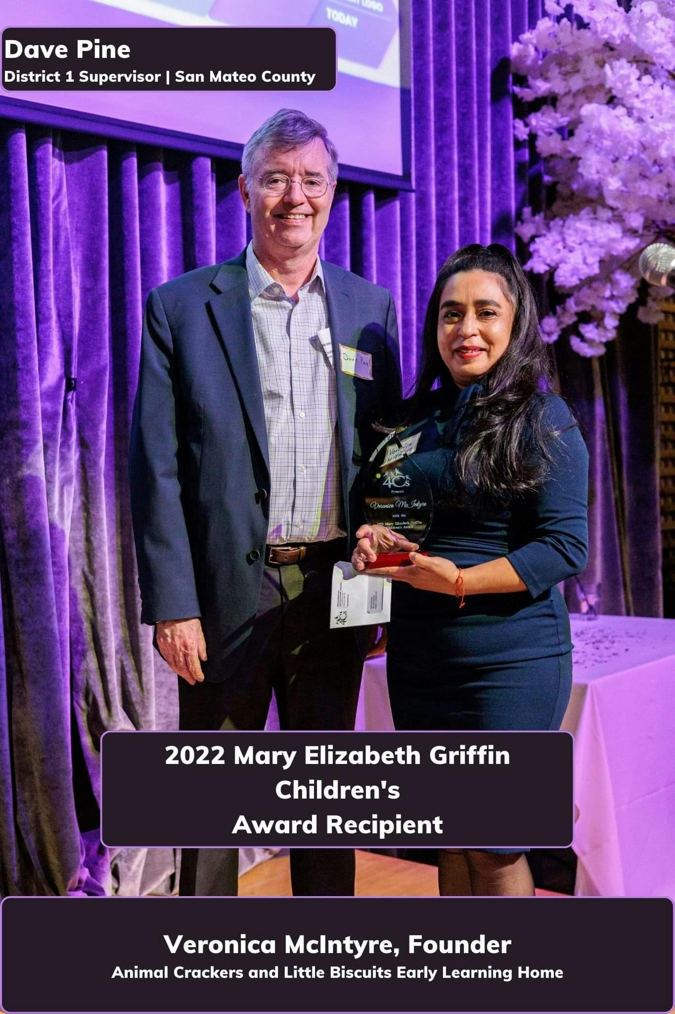 Two people standing, one holding an award