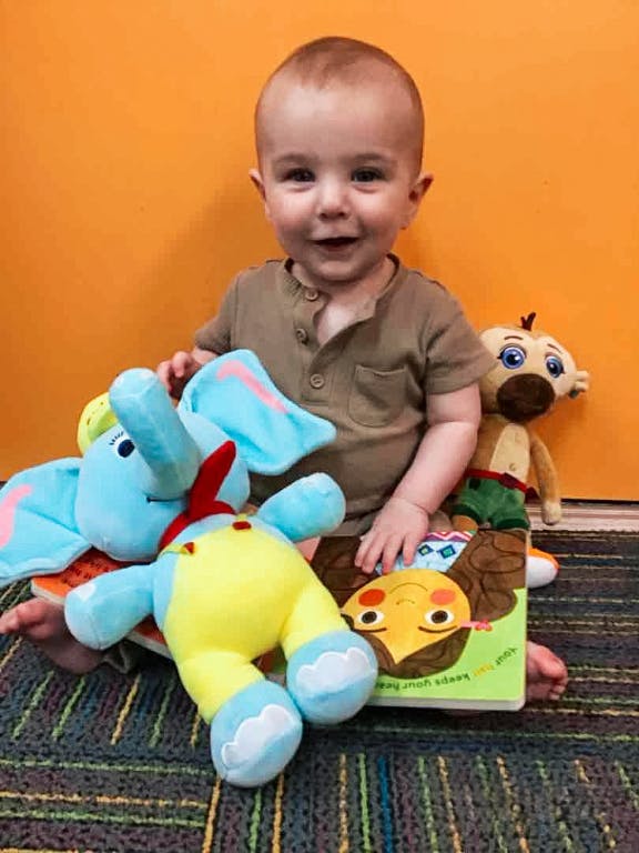 Child sitting with stuffed animals and a book